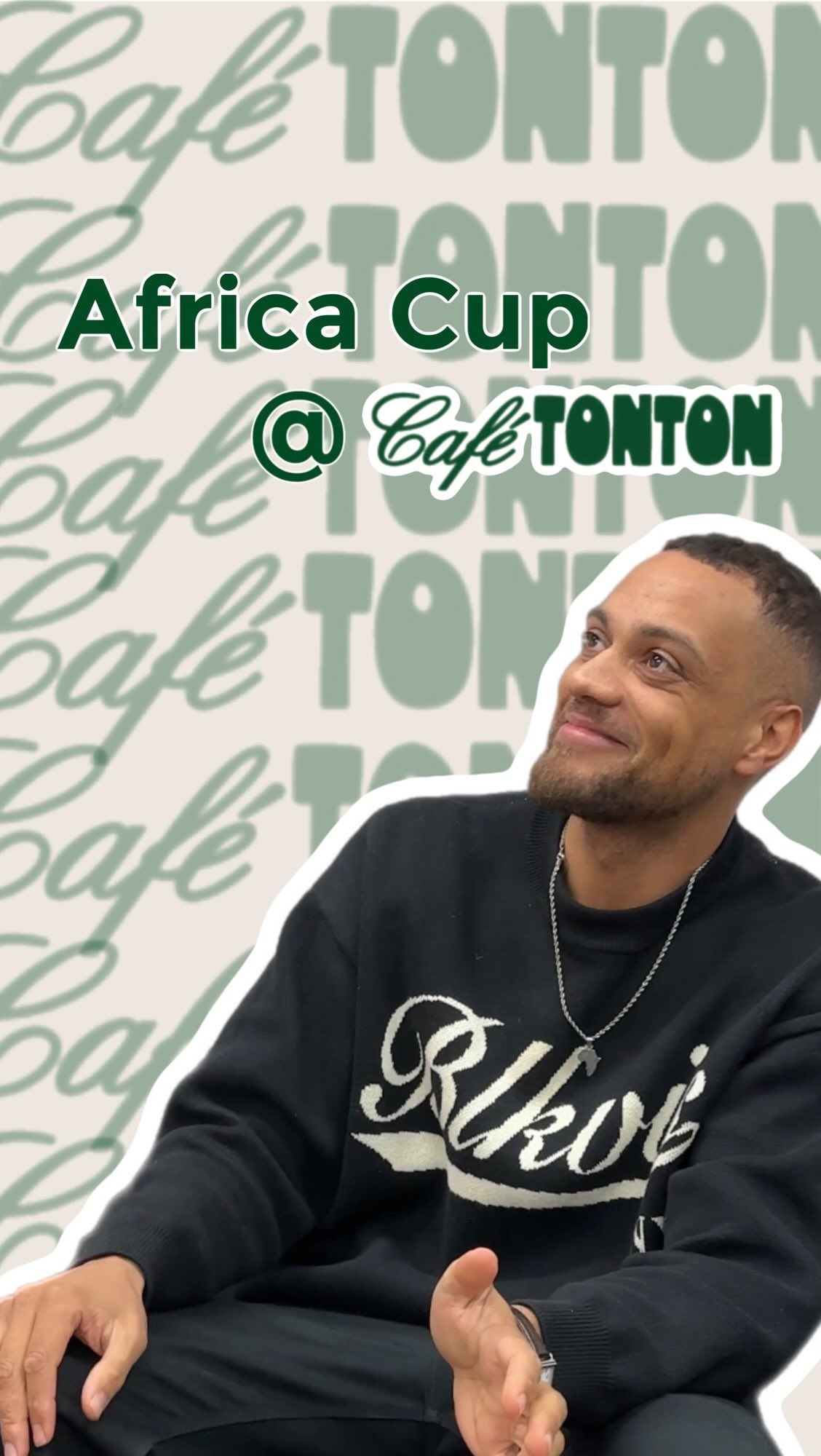 A smiling man in a dark sweater at Café TonTon during the Africa Cup