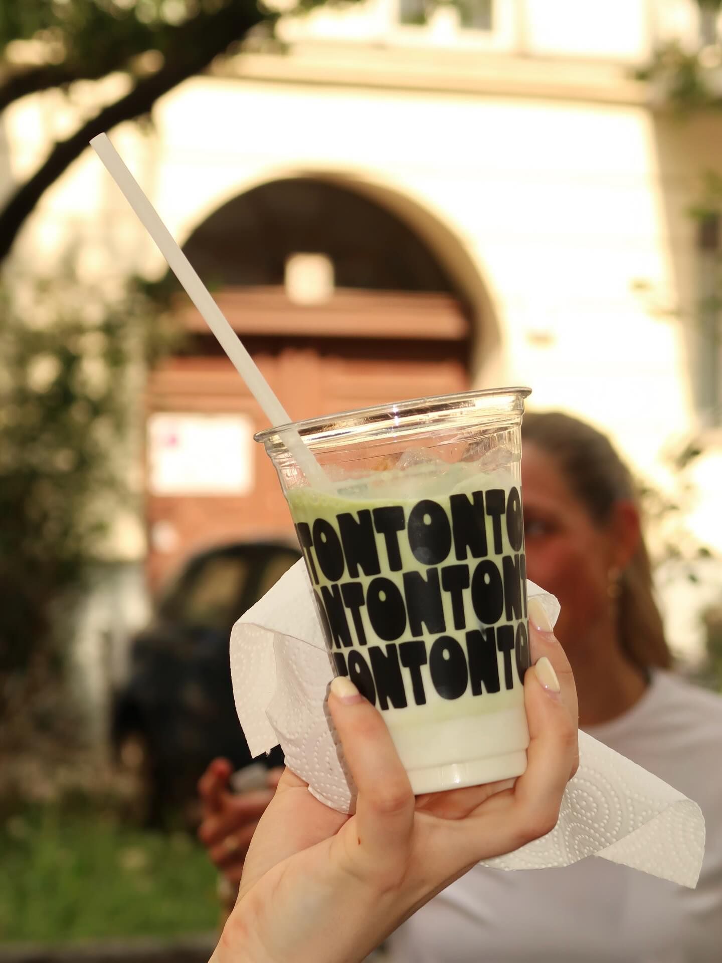 A hand holding an iced matcha in a TonTon cup